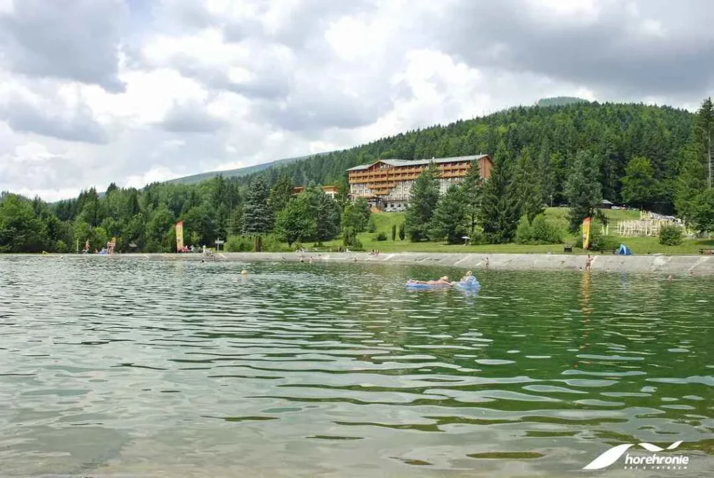 Prírodné kúpalisko Tále s hotelom v pozadí a kúpajúcimi sa návštevníkmi